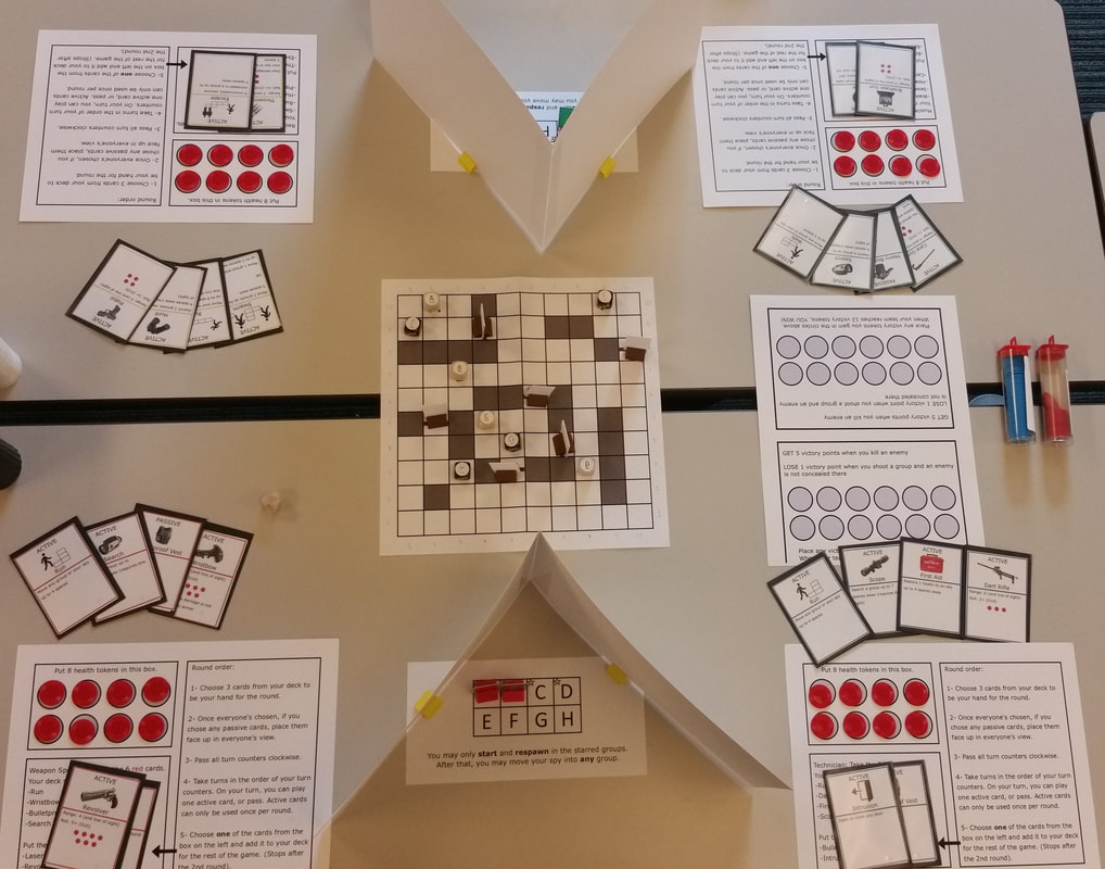 Photo of a table setup of my tabletop game, High Roller, Low Profile, with a board in the middle, and two players' character sheets, cards, and visibility shield on either side.